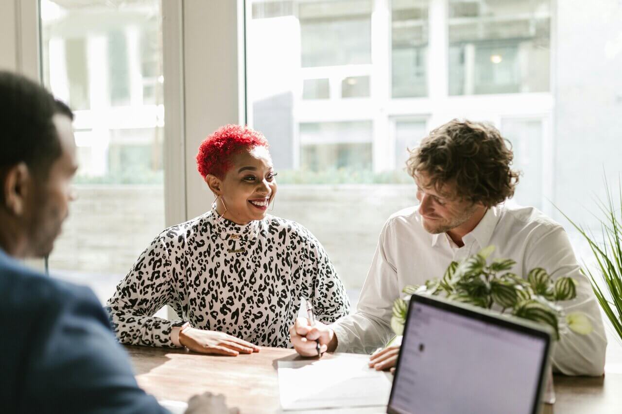 Female accountant with red hair smiling at male colleague in a meeting 