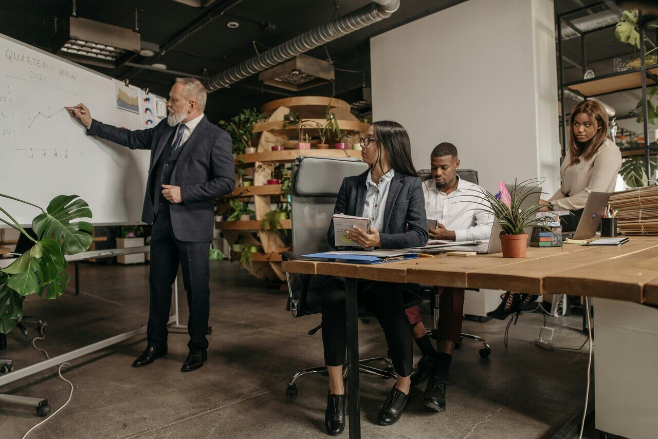 Four colleagues in a meeting in an open office discussing green initiatives 