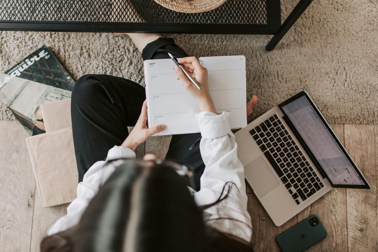 Aspiring accountant sitting on floor writing in her diary 