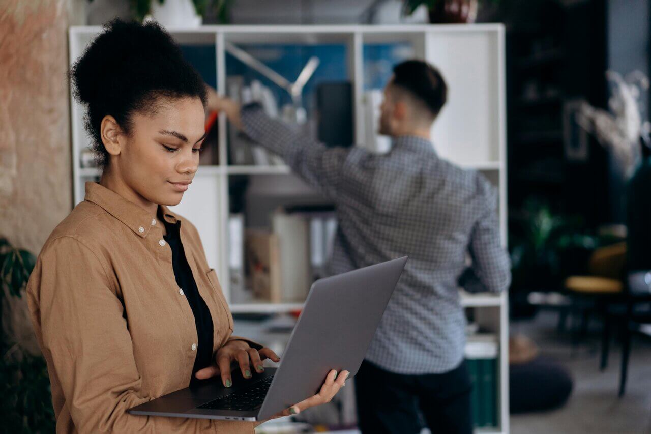 Young black female researching AAT exams on her laptop beside a coworker