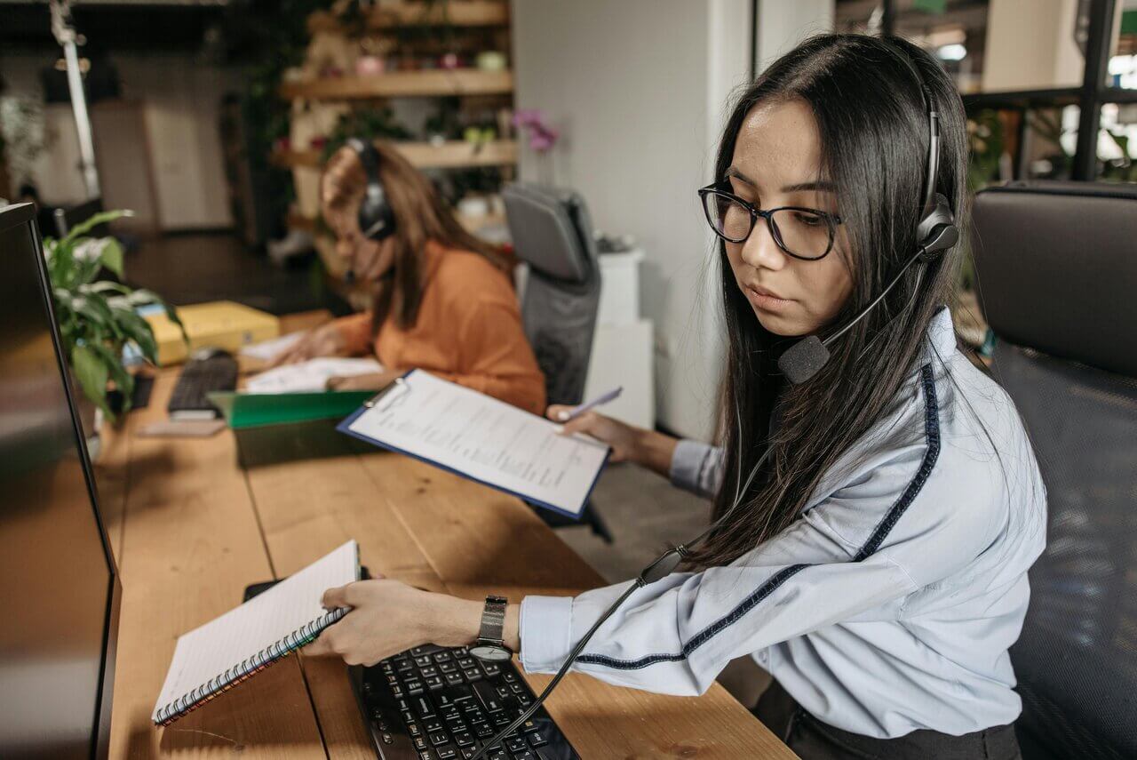Young female professional with headphones on and notepad