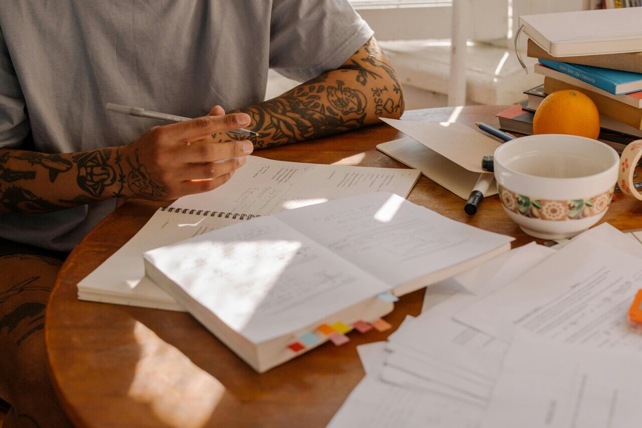 Tattooed individual comparing notes on how much an AAT qualification costs 