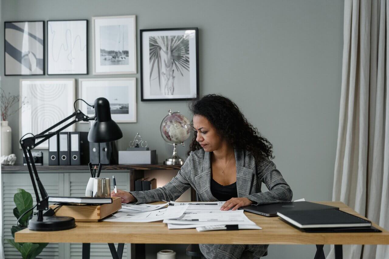 Black professional female at desk on laptop and writing